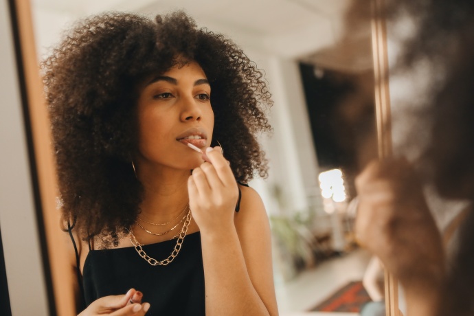 Jeune femme se maquiller dans le miroir